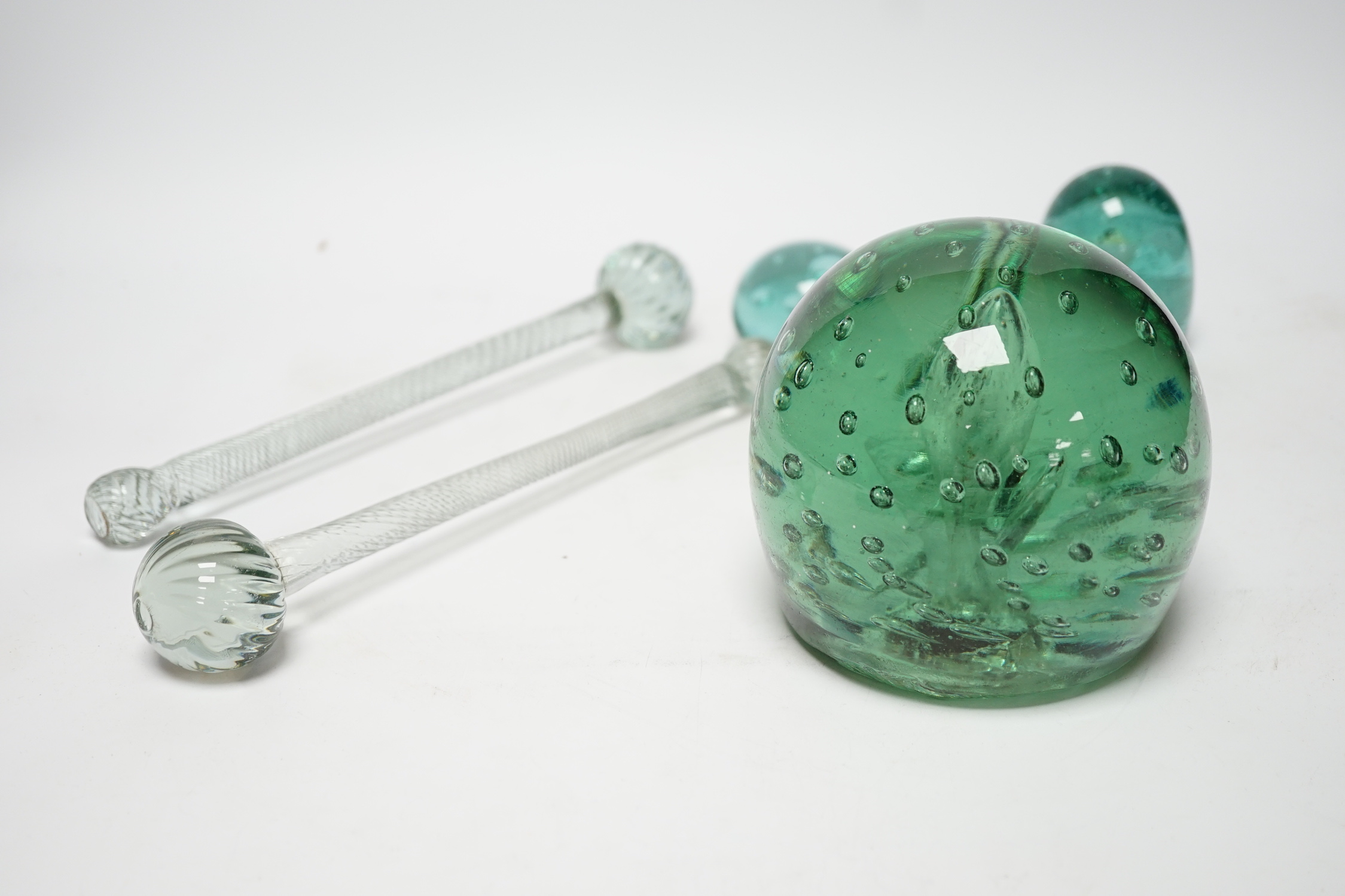 Three 19th century green glass Stourbridge dumps, one large, 12cm diam. and two small, 6cm diam., together with two glass batons, 25cm long